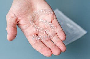 person holding Invisalign aligners