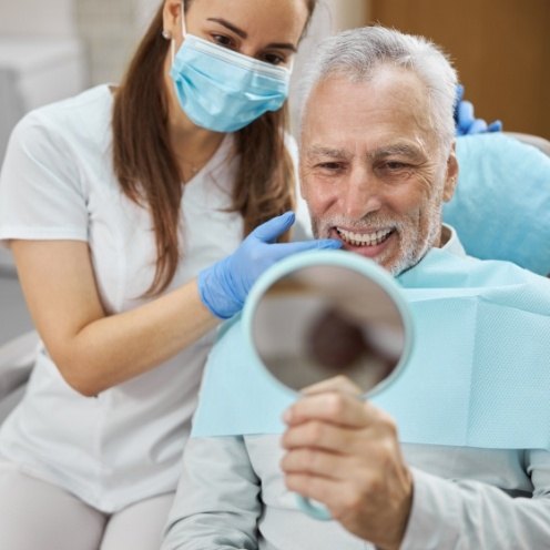 Dental team member showing senior patient his new smile