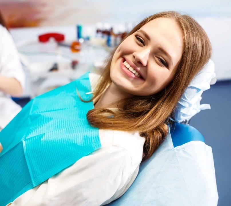 Woman smiling in dental chair thanks to gum disease treatment