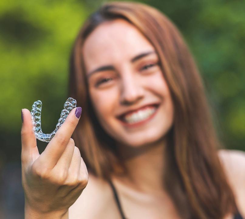 Young woman holding an Invisalign aligner