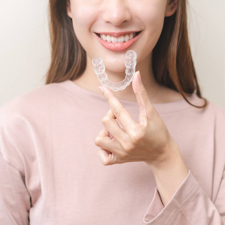 Young women holding an Invisalign tray