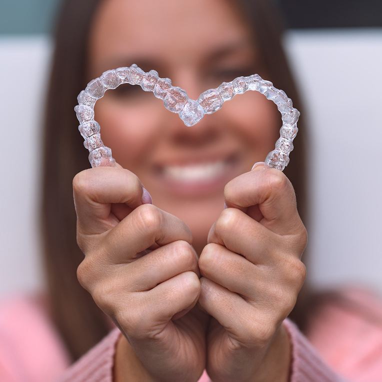 Someone making a heart with Invisalign trays