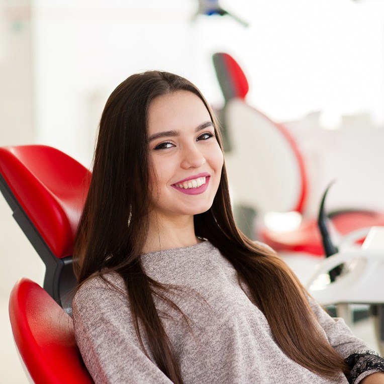 young woman smiling while sitting in treatment chair 