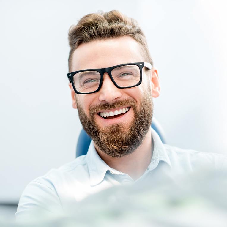 man smiling while sitting in treatment chair