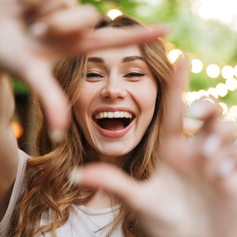 young woman smiling and framing face with hands