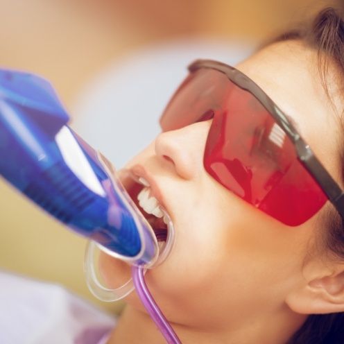 Young woman receiving fluoride treatment in dental office