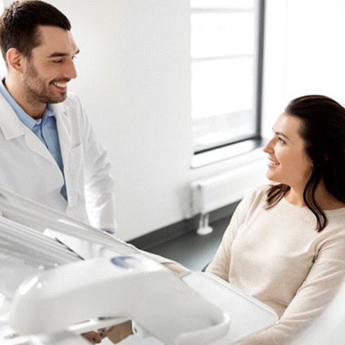 Dentist smiling at patient sitting in dental treatment chair