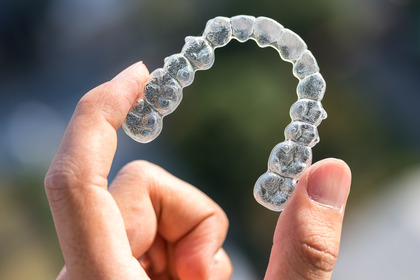 closeup of someone holding Invisalign aligner 